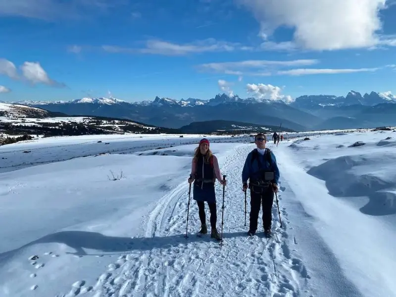 Zwei Personen laufen im Schnee in einer winterlichen Berglandschaft.